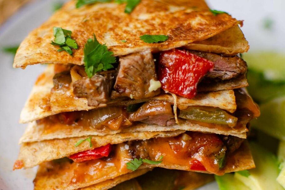 Stack of quesadillas on top of each other with sliced avocado on a plate.