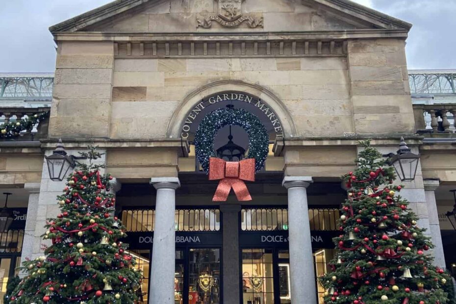 Outside of Covent Garden London at Christmas with two Christmas trees and a large red bow