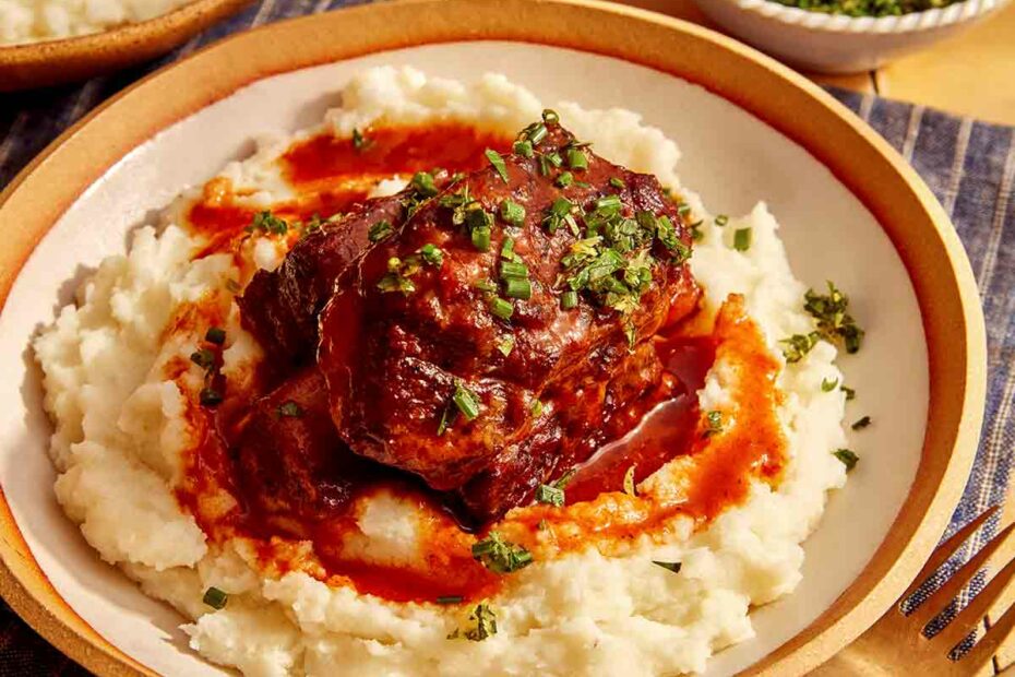 Braised short ribs on top of mashed potatoes in a bowl.