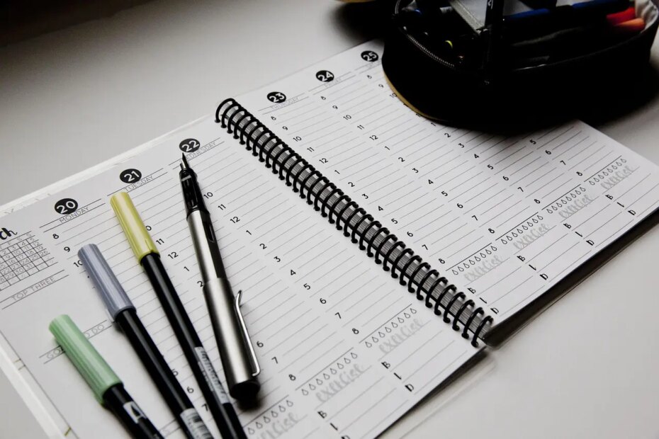 Open planner with pens on a desk, symbolizing realistic goal setting, habit building, and planning for the new year.