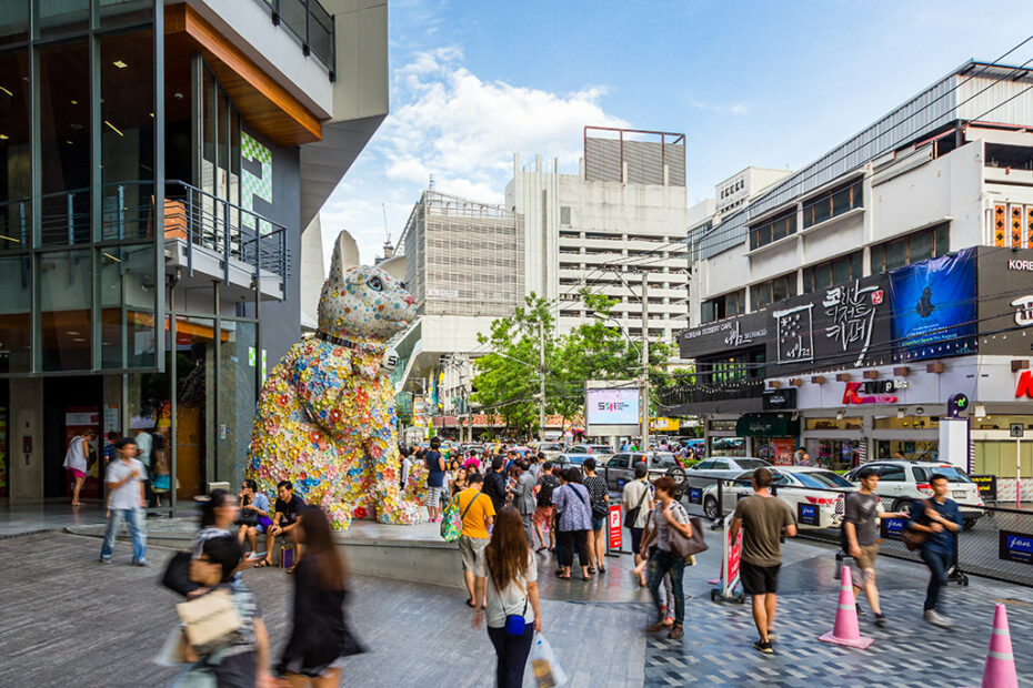 Bangkok’s Siam district with a colorful waving cat statue and people walking by