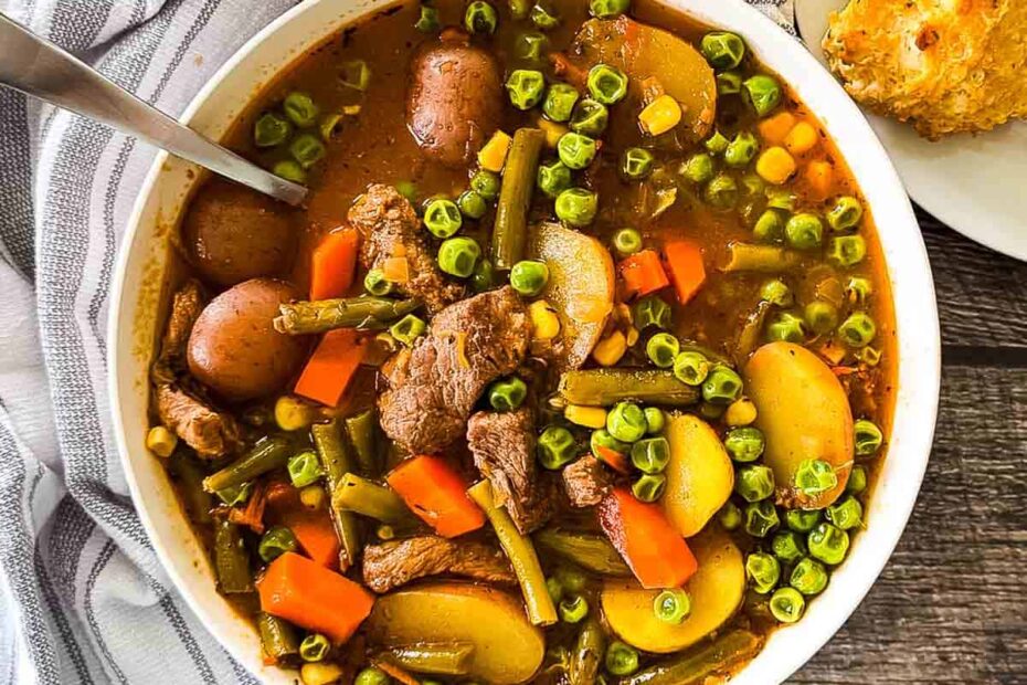 Old-fashioned beef vegetable soup with tender beef, potatoes, carrots, peas, and green beans in a rich broth, served in a white bowl.