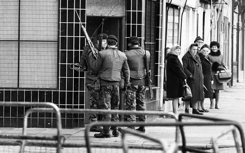 Street scene in Belfast during the Troubles. British soldiers stand next to a group of elderly ladies on a street corner.